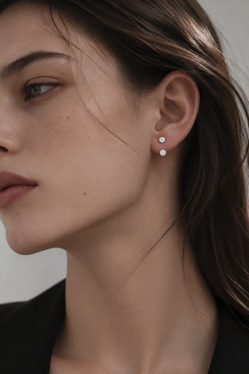 HERIMYST double diamond stud earrings with a smaller upper diamond and larger lower diamond worn on the earlobe.