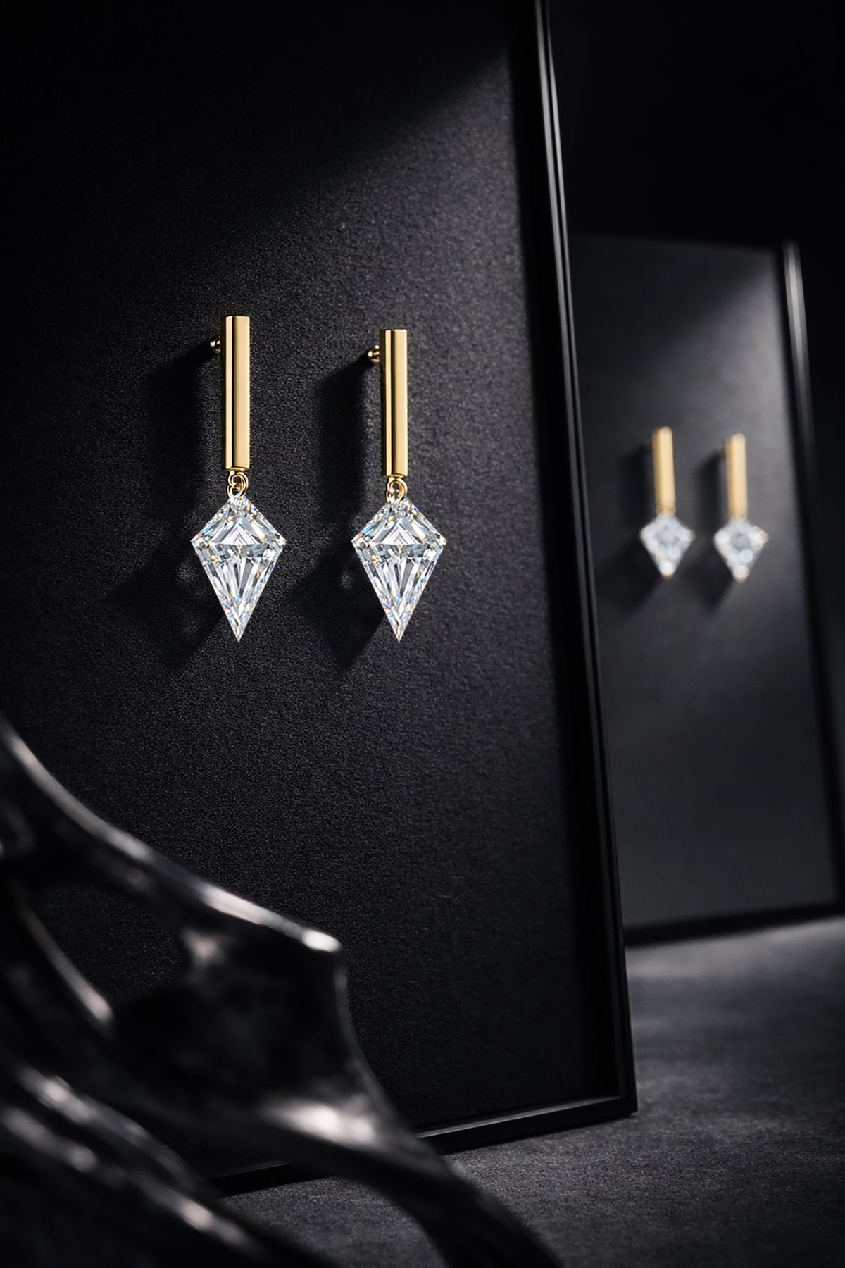 Two single kite-cut floating diamond drop studs displayed together on a black jewelry stand