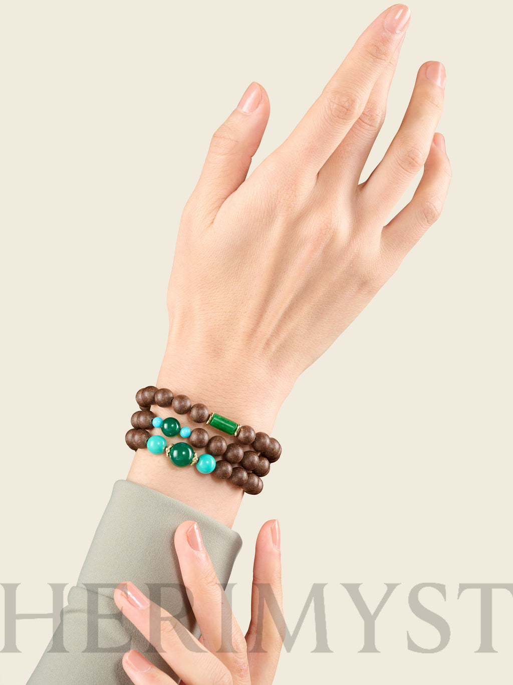 Layered agarwood incense bead bracelets with green jade and turquoise accents worn on wrist, styled with a minimalist neutral-toned outfit.
