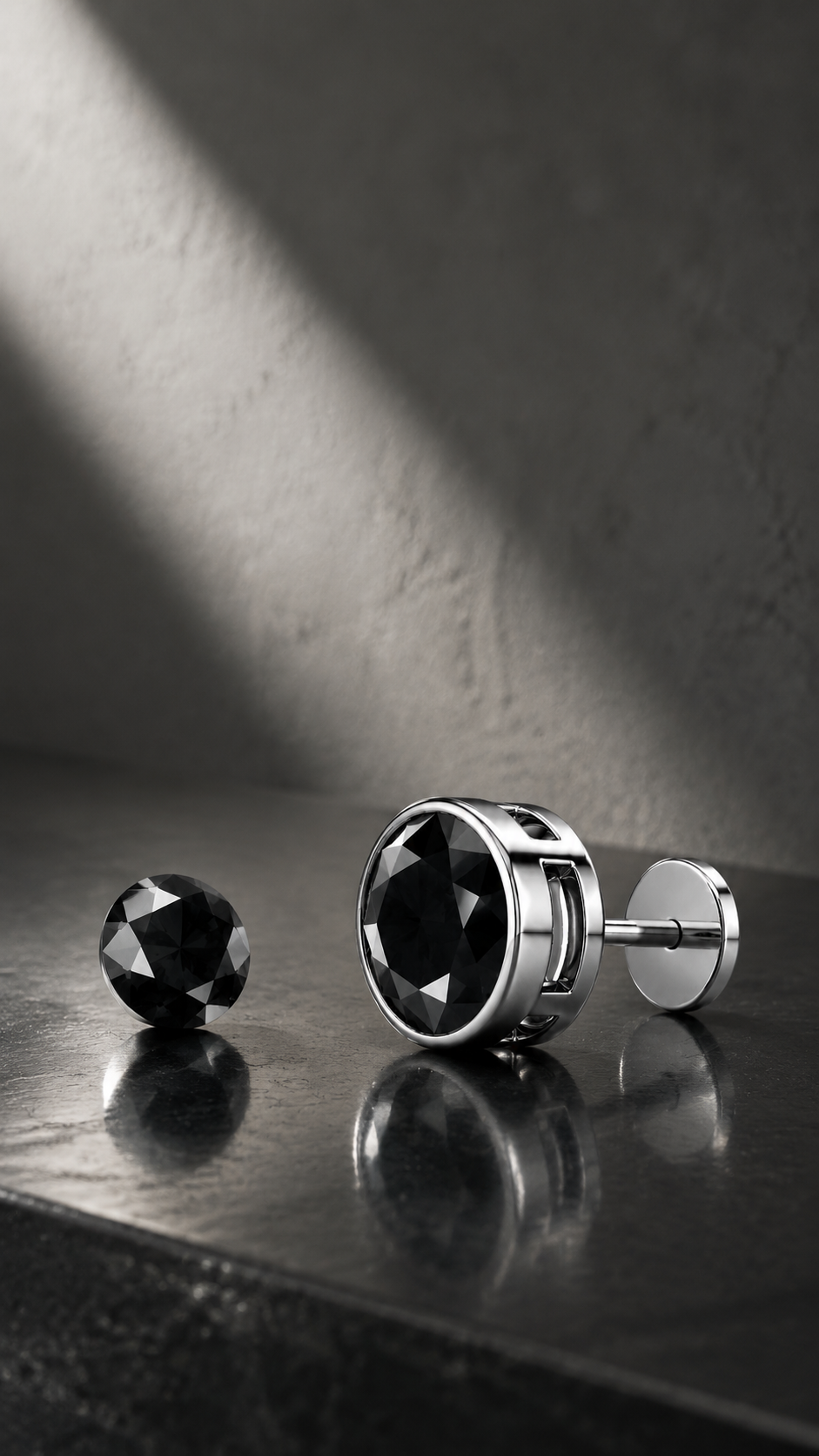 Black diamond bezel stud earring in 14K white gold beside a loose round black diamond