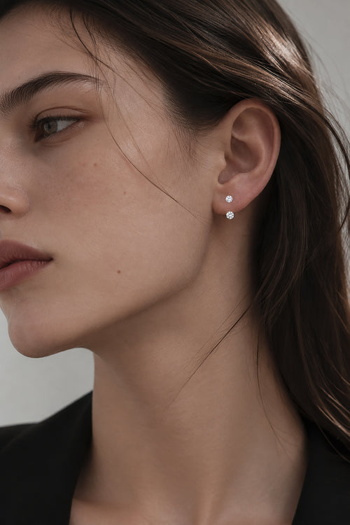 Woman wearing one pair of floating double diamond stud earrings with two round lab-grown diamonds arranged vertically