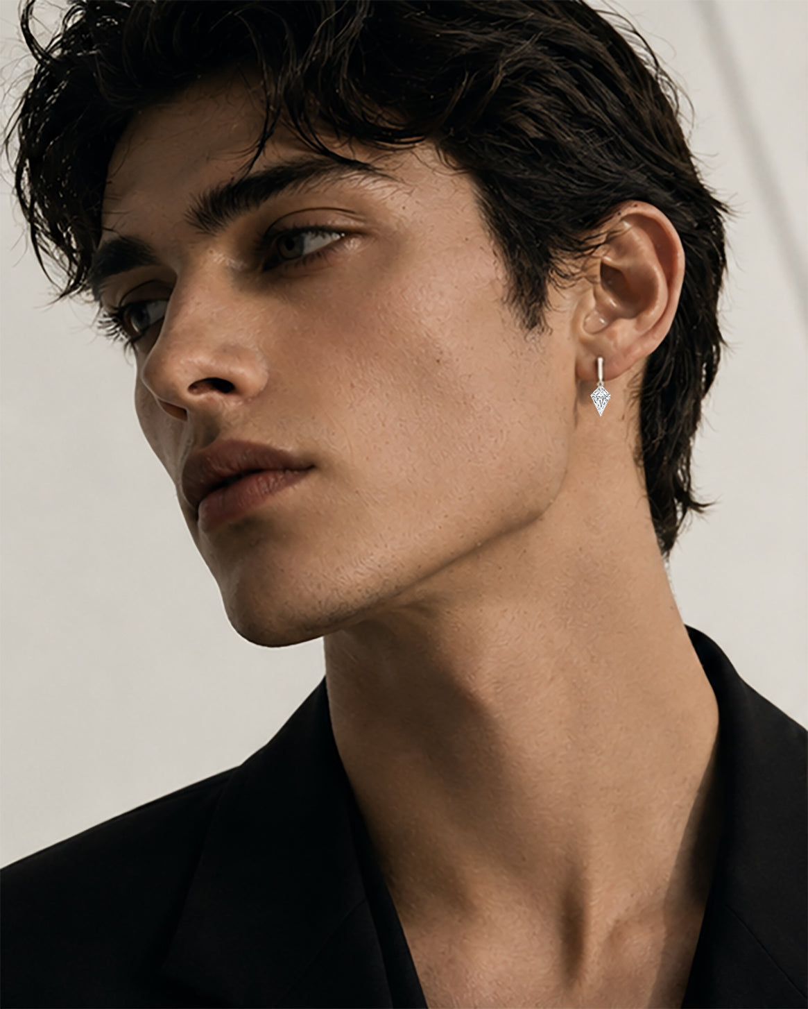 Male model wearing a single kite-cut floating lab-grown diamond drop stud in 14K yellow gold