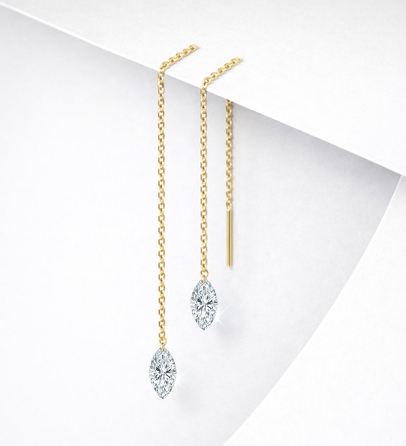 Pair of 14K yellow gold floating diamond threader earrings with lab-grown marquise-cut diamonds on a white geometric background