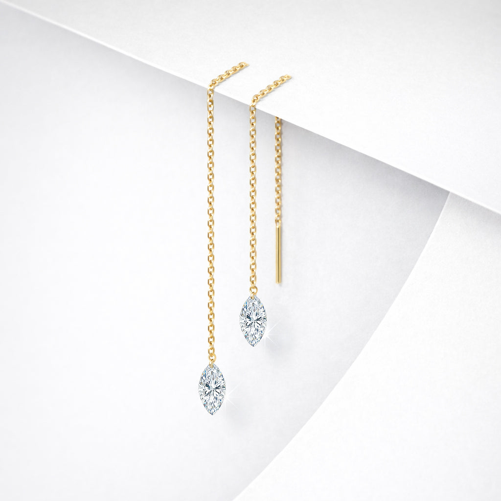 Pair of 14K yellow gold floating diamond threader earrings with lab-grown marquise-cut diamonds on a white geometric background