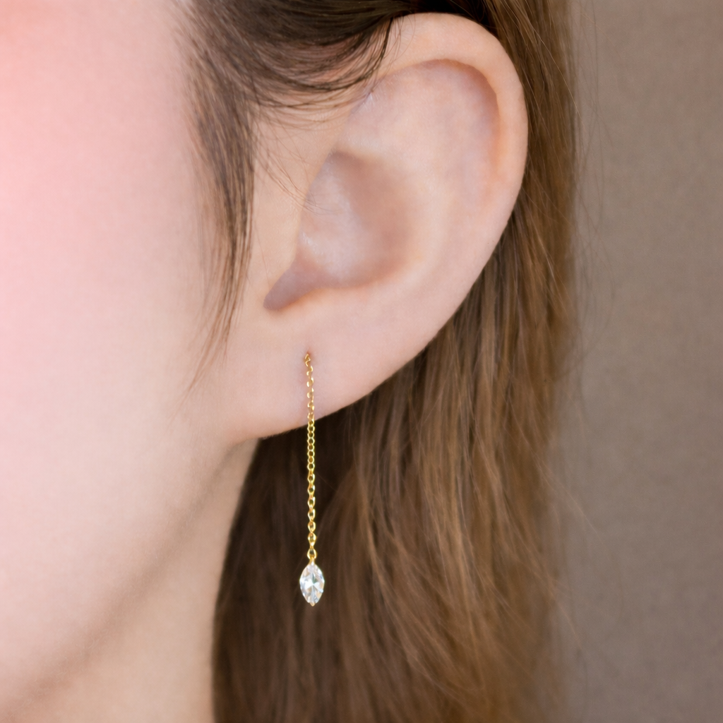Close-up of a 14K gold threader earring with a small marquise-cut diamond, showing refined facets and natural light reflection on the diamond surface.