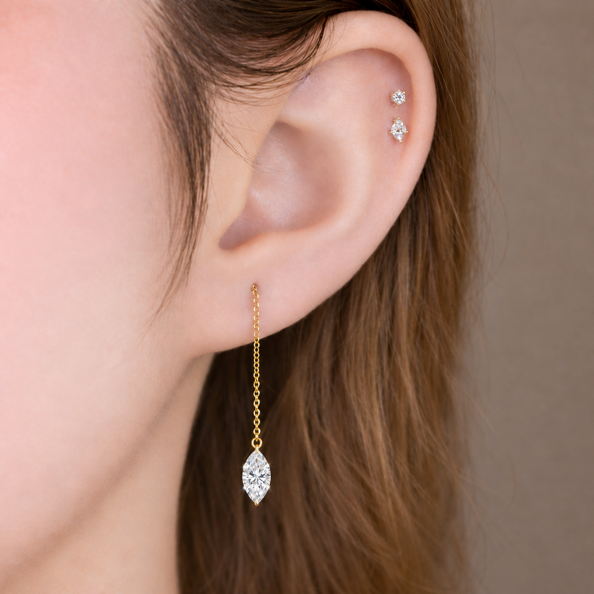 Close-up of an ear wearing a 14K yellow gold floating diamond threader earring with a lab-grown marquise-cut diamond