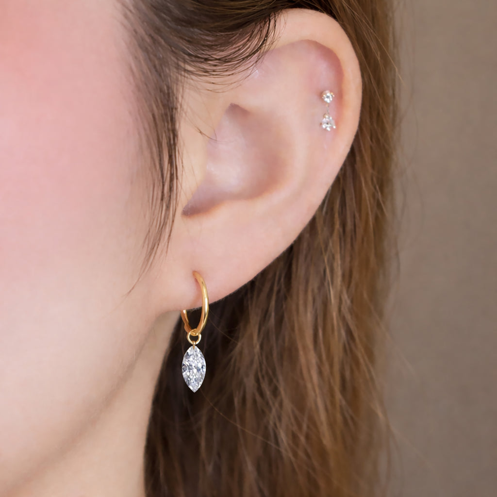 Model wearing a marquise-cut lab-grown diamond drop huggie earring in 14K yellow gold