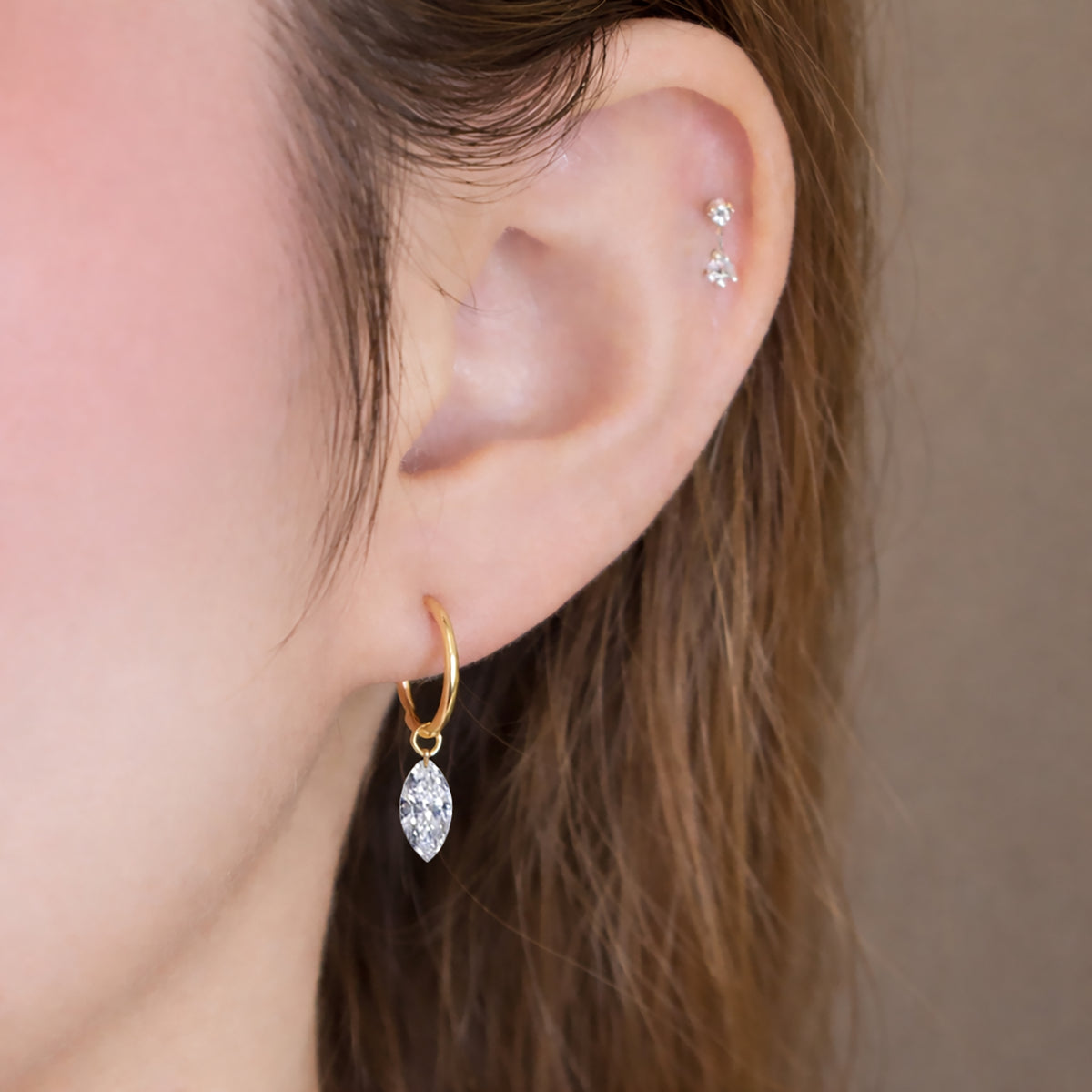 Model wearing a marquise-cut lab-grown diamond drop huggie earring in 14K yellow gold