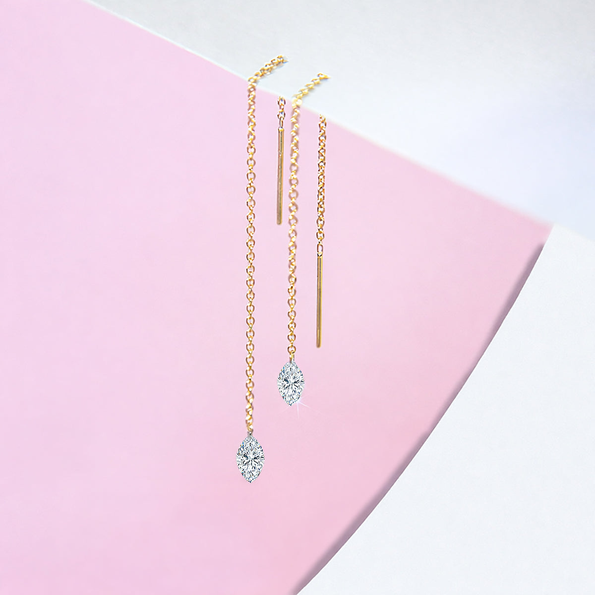 14K yellow gold floating diamond threader earrings with lab-grown marquise-cut diamonds displayed on a pink geometric background