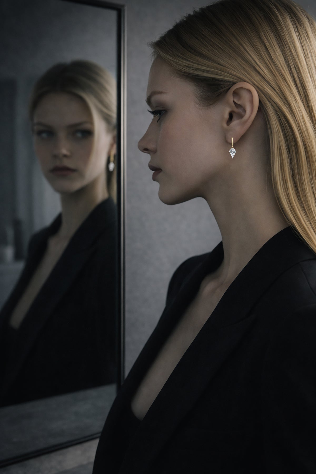 Female model wearing a single kite-cut floating lab-grown diamond drop stud beside a mirror